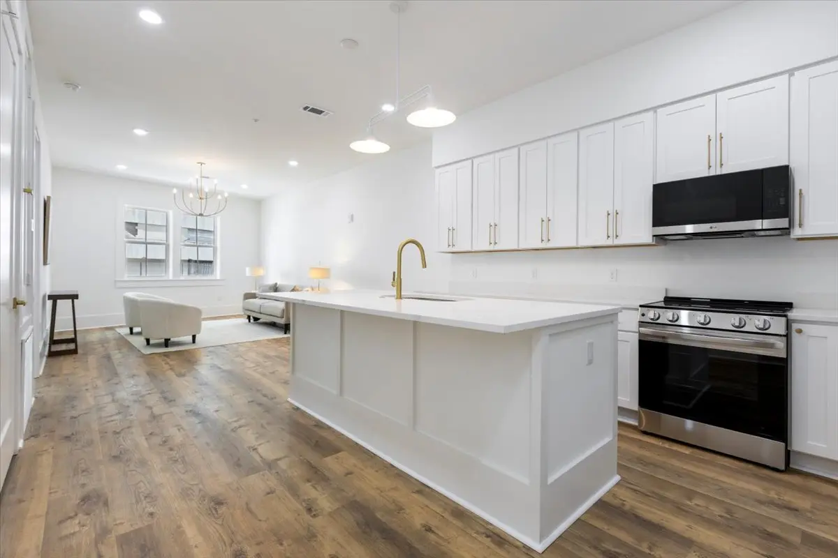 Open kitchen and living area with warm oak-look flooring installed by New Orleans Flooring